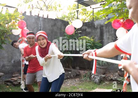 Tre persone in una squadra hanno cercato di tirare la corda durante la gara di Torg-of-war alle celebrazioni Indonesia Independence Day Foto Stock