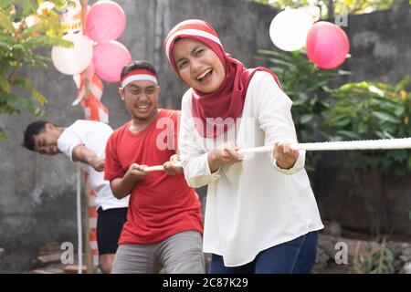 Le giovani donne asiatiche gridano con entusiasmo quando tirano la corda durante il rimorchiatore della partita di guerra in celebrazione del 17 agosto, il giorno dell'indipendenza dell'Indonesia Foto Stock