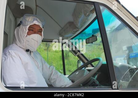 Bhaktapur, Nepal. 16 luglio 2020. Il driver dell'ambulanza Buddha Krishna Baga Shrestha si siede al volante di un'ambulanza con una guardia della bocca e un vestito protettivo. A causa della mancanza di indumenti protettivi, molti conducenti hanno smesso di lavorare durante la pandemia di Corona. L'età di 49 anni che ancora fa il suo lavoro è una celebrità locale perché da anni gioca il demone al Jibro Chedne Jatra, un festival di piercing della lingua. (A dpa 'UN demone aiuta i pazienti di Corona in Nepal') Credit: Roshan Sedhai/dpa/Alamy Live News Foto Stock