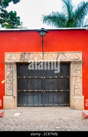 Facciata in stile coloniale nella città di la Antigua Guatemala, con camino e balconi in ferro battuto, strada acciottolata e cielo blu. Foto Stock