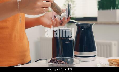 Utilizzare il macinacaffè per preparare caffè fresco per la colazione. Casalinga a casa, preparare caffè macinato fresco in cucina per colazione, bere, macinare caffè espresso prima di andare al lavoro Foto Stock