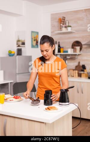 Con la preparazione del caffè la mattina per il marito utilizzando i chicchi di caffè. Casalinga a casa, preparare caffè macinato fresco in cucina per colazione, bere, macinare caffè espresso prima di andare al lavoro Foto Stock