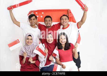 Giornata della bandiera di Singapore. Giovane gioioso gruppo di persone detiene la bandiera di Singapore celebrare insieme del giorno di indipendenza Foto Stock