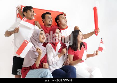 Giornata della bandiera di Singapore. Giovane gioioso gruppo di persone detiene la bandiera di Singapore celebrare insieme del giorno di indipendenza Foto Stock