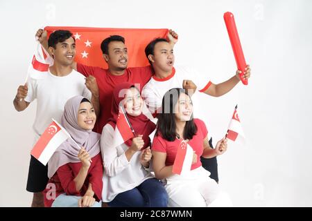 Giornata della bandiera di Singapore. Giovane gioioso gruppo di persone detiene la bandiera di Singapore celebrare insieme del giorno di indipendenza Foto Stock