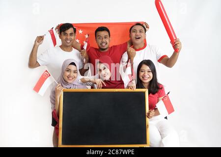 Giornata della bandiera di Singapore. Giovane gioioso gruppo di persone detiene la bandiera di Singapore celebrare insieme del giorno di indipendenza Foto Stock