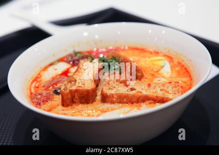 Laksa è una zuppa di noodle piccante popolare nella cucina Peranakan del Sud-est asiatico, che può essere consumata per colazione o pranzo a Singapore. Foto Stock