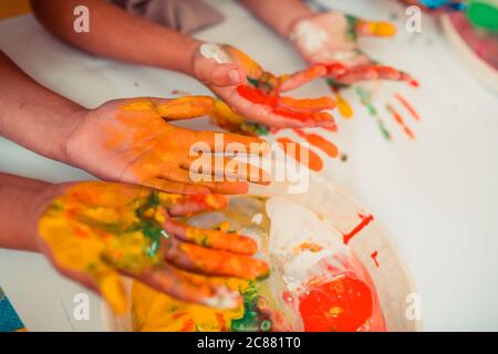 I bambini che mettono la vernice sulle loro mani durante le pratiche di arte Foto Stock