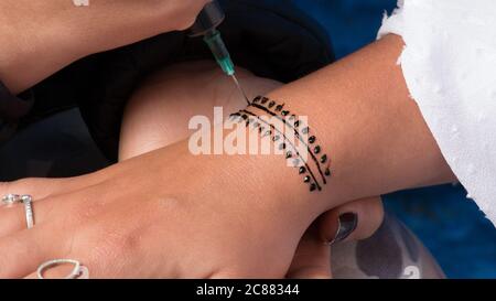 Artista che applica tatuaggio henné sulla mano della donna. Mehndi è tradizionale indiano decorazione arte primo piano mani Foto Stock