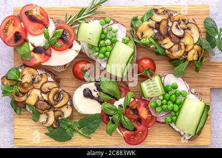 Sano assortimento di toast vegetariani con funghi, pomodori, piselli verdi e cetrioli. Foto Stock