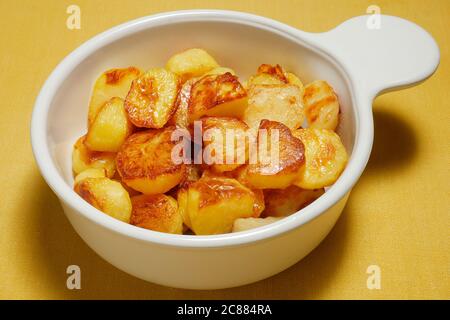 PATATE BRAVAS IN UN RECIPIENTE BIANCO CON SALSA DI POMODORO, PANNA ACIDA VEGANA, BASILICO Foto Stock