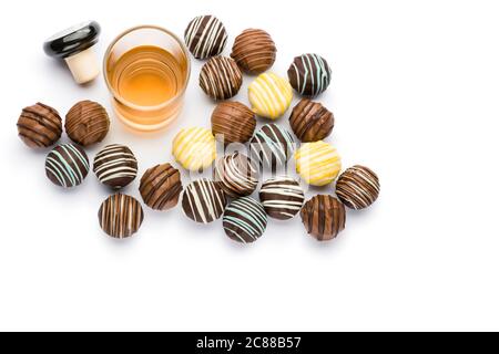 pasticceria assortita di cioccolatini ripieni con bicchiere di liquore e spazio per fotocopie su sfondo bianco Foto Stock