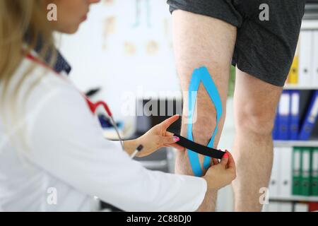 Il medico collana un nastro elastico alla gamba del paziente Foto Stock