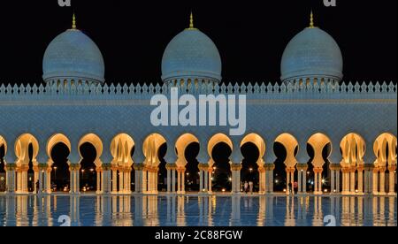 La Grande Moschea dello Sceicco Zayed, Abu Dhabi di notte con riflessione in acqua Foto Stock