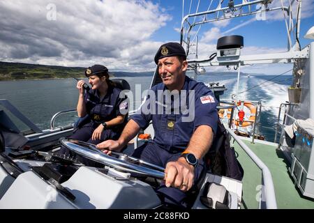 Comandante Lt Rebecca Anderson Royal Navy (destra) all'estero HMS Biter con CPO (AWT) Adam Cooper al timone durante la manovra di chiusura della nave lungo la costa nord dell'Antrim. La pandemia del coronavirus ha lanciato sfide logistiche a bordo di una nave da guerra che allena gli ufficiali comandanti del futuro. Foto Stock