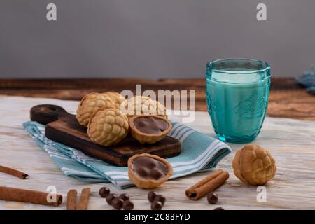 biscotti al cioccolato e bicchiere di latte sullo sfondo. noci da forno con cioccolato e cannella Foto Stock