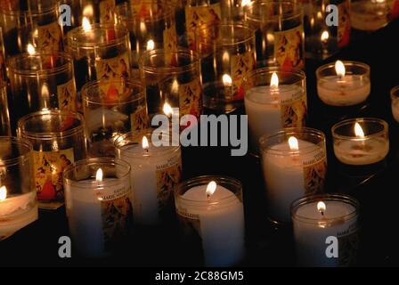 Le candele votive che tremano illuminano piccoli spazi all'interno scuro della Basilica di Sainte-Marie-Madeleine, la chiesa di un'ex abbazia benedettina a Vézelay, Yonne, Borgogna, Francia. La chiesa fu ricostruita e ampliata nel 12 ° secolo per far fronte a orde di pellegrini che viaggiavano per venerare le ossa conservate nella cripta, creduto essere reliquie di Santa Maria Maddalena. La chiesa abbaziale è stata aggiunta alla lista UNESCO dei siti Patrimonio Mondiale dell'Umanità nel 1979. Foto Stock