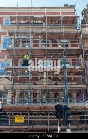 Vista di uomini non identificati che lavorano su ponteggi su un edificio in Infirmary Street, Leeds Foto Stock