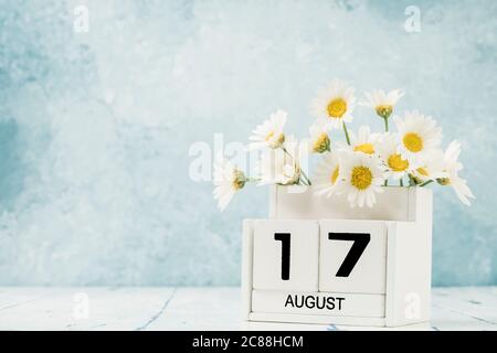 Calendario cubo bianco per agosto decorato con fiori margherita su blu con spazio copia Foto Stock