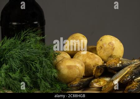 Filetto di aringa con patate giovani e onionpatate giovani e pesce affumicato, aneto sulla tavola, una bottiglia di birra scura Foto Stock