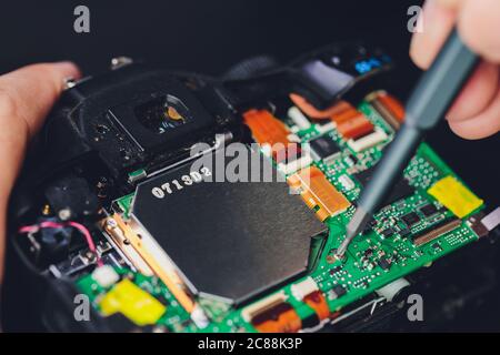 I minitures del tecnico e del tecnico stanno fissando il complessivo della scatola dello specchio della telecamera, gli operai di Miniture stanno controllando l'ottica ed effettuano la manutenzione e la pulizia Foto Stock