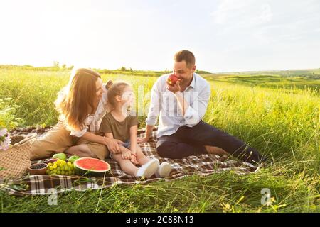 Buona famiglia che gioca con frutta in un picnic all'aperto Foto Stock