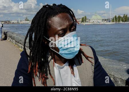 Un giovane africano indossa una maschera medica per proteggersi dall'epidemia di coronavirus. Primo piano . Un uomo in sedia a rotelle. Estate giorno di sole. Foto di alta qualità Foto Stock