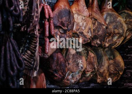 Shot di cosce di maiale e salsicce appesi nella negozio Foto Stock