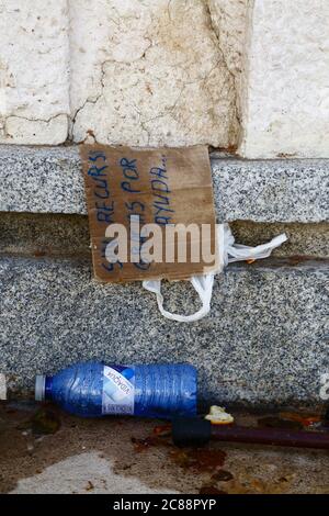 22 luglio 2020, Madrid, Spagna: Un bastone abbandonato, bottiglia d'acqua di plastica e cartoncino che apparteneva ad un mendicante in una piazza nel centro di Madrid. Il segno dice 'in recursos gracias por ayuda' / 'senza risorse / reddito grazie per l'assistenza'. La notte precedente pioveva molto a Madrid, il cartello era probabilmente lasciato da qualcuno che aveva dormito per strada e doveva cercare rifugio Foto Stock