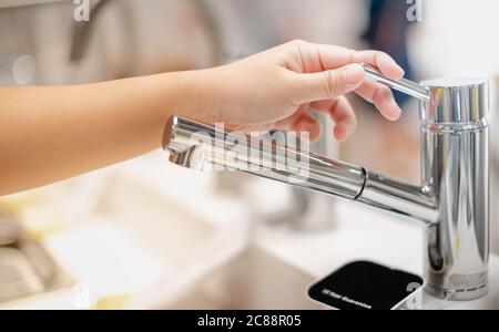 Mano femminile scelta del rubinetto di cucina in acciaio inossidabile da utilizzare all'interno della casa e il nuovo design per decorare in cucina e nel wc. Foto Stock