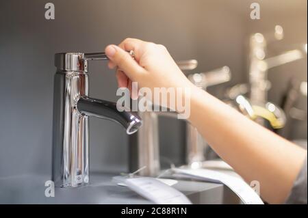 Mano femminile scelta del rubinetto di cucina in acciaio inossidabile da utilizzare all'interno della casa e il nuovo design per decorare in cucina e nel wc. Foto Stock