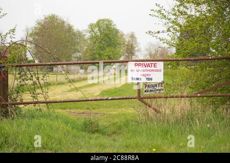 Punto di interesse poco profondo di un cartello privato realizzato localmente visto all'ingresso di un pascolo privato. Fissato da un cancello metallico per evitare i danni al buio Foto Stock