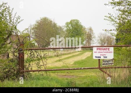 Punto di interesse poco profondo di un cartello privato realizzato localmente visto all'ingresso di un pascolo privato. Fissato da un cancello metallico per evitare i danni al buio Foto Stock