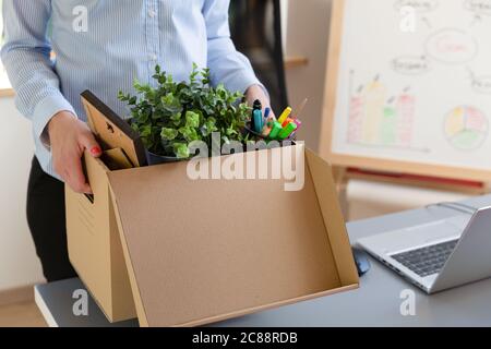 Bella donna di affari che porta una scatola di roba di ufficio. Promozione di nuovi lavori o concetto di abbandono di posti di lavoro. Foto Stock