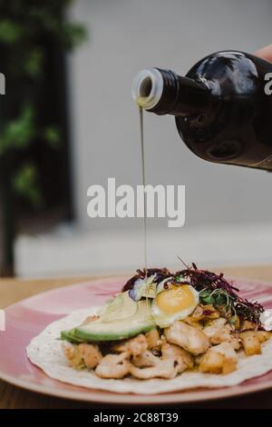 Erogazione verticale di olio da una bottiglia un'insalata di verdure di pollo Foto Stock