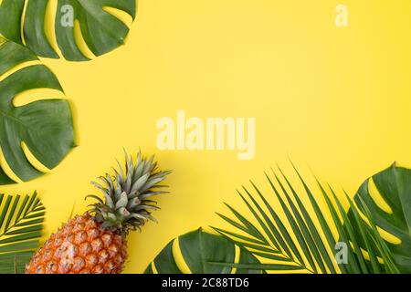 Bella ananas su palme tropicali foglie monstera isolato su sfondo giallo pastello brillante, vista dall'alto, piatto, sopra la frutta estiva. Foto Stock