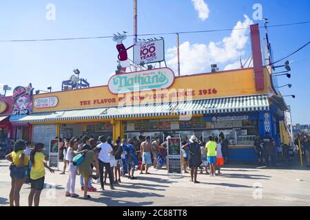 La maggior parte delle persone sono senza maskless mentre aspettano di comprare un hot dog al famoso Nathan's sulla passerella a Coney Island durante la pandemia del covid-19 nell'estate del 2020. Foto Stock