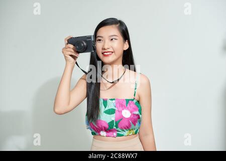 Attraente donna asiatica energica felicemente tenendo cemara isolato su sfondo bianco studio Foto Stock