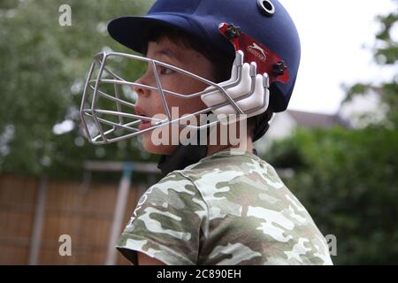 Bambino in ingranaggio di cricket che gioca pratica di cricket a casa nel giardino del Regno Unito durante il blocco, 2020 Foto Stock