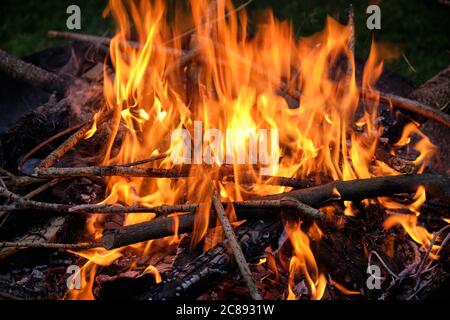 Un falò naturale con bastoni e rami di legno sta bruciando in una ciotola di fuoco di notte. Visto in Germania nel mese di luglio. Foto Stock