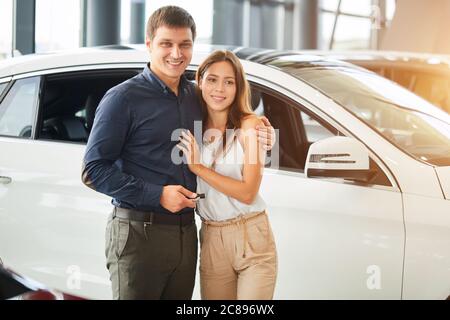 Ora il suo sogno si avvera. Il marito di successo acquista un'auto per la sua amorevole moglie di moda all'auto motor show, fare un regalo per il loro anniversario Foto Stock