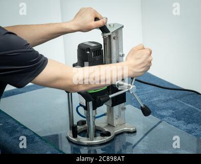 Un lavoratore perfora un foro nel vetro. Foto Stock