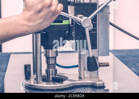 Un lavoratore perfora un foro nel vetro. Foto Stock