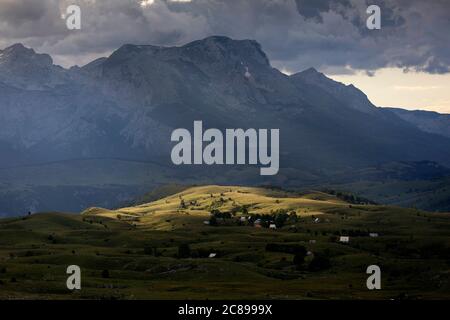 Luce serale sulle case su un prato in paesaggio di montagna, Parco Nazionale Durmentor, Montenegro Foto Stock
