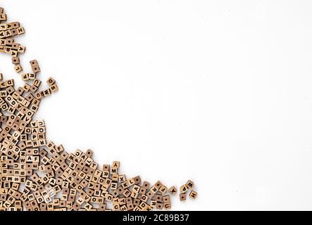 Piccole perle di legno cubico con varie lettere sparse su sfondo bianco, vista dall'alto Foto Stock