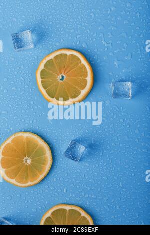 Fette di arancio fresco su fondo blu con ghiaccio. Foto Stock