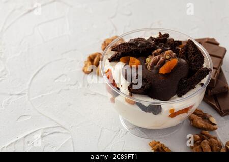 Dessert in mousse di cacao in scatola trasparente di plastica su superficie grigia Foto Stock