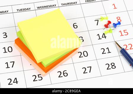 note adesive con perni e penna sul calendario Foto Stock