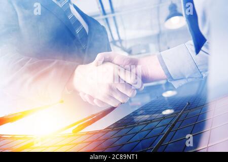 Due uomini d'affari si stringono le mani d'accordo. Doppia esposizione con effetto luminoso Foto Stock