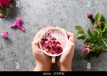 Latte di luna di rosa in mani del bambino su grigio. Ayurveda bevanda calda. Bello in caso di insonnia. Foto Stock